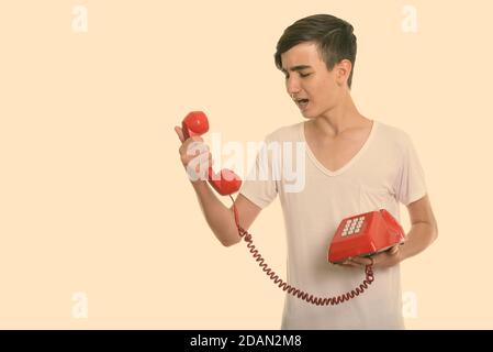 Studio di un giovane ragazzo persiano arrabbiato che gridava vecchio telefono Foto Stock