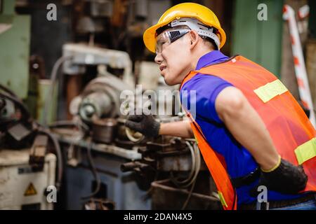 I lavoratori asiatici che lavorano sodo nelle fabbriche industriali soffrono di dolore alla schiena durante il lavoro sulle macchine. Foto Stock