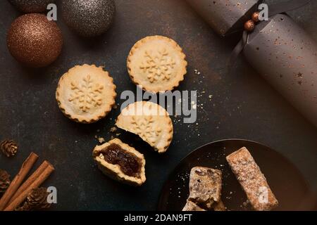 Stollen barre su un piatto nero e mince torte circondato Da decorazioni di Natale Foto Stock