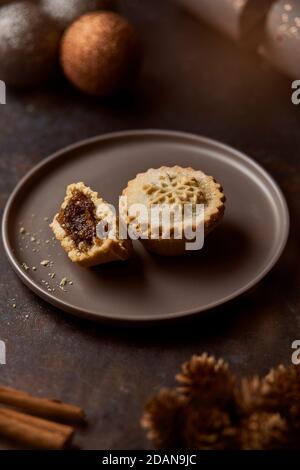 Mince torte su un piatto grigio circondato da decorazioni natalizie Foto Stock