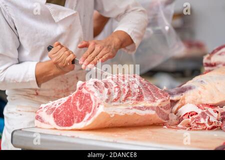 Industria della carne, macellaio ha tagliato la carne cruda con un coltello a tavola nel macello, Wagyu Beef Foto Stock