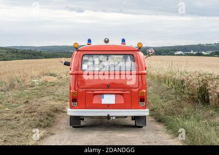 Coppia di nozze in Oldtimer VW T1 fuoco motore rosso fuoco macchina classica auto guida sulla strada. Foto Stock