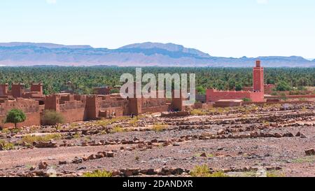 Adobe edifici in primo piano e la foresta di palme e le montagne della valle di Draa, Zagora, Marocco. Foto Stock