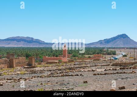 Adobe edifici in primo piano e la foresta di palme e le montagne della valle di Draa, Zagora, Marocco. Foto Stock