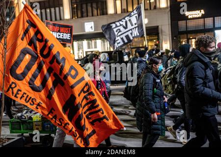 Il protestore tiene la bandiera del fascismo di rifiuto e un altro tiene una bandiera nera della materia di vite. Detroit Will Breathe, un gruppo attivista contro la brutalità della polizia e per le vite nere, ha organizzato una marcia notturna 'Chief Craig rassegnazione' nel centro di Detroit. Questa particolare protesta si è concentrata sul trattamento riservato dal capo della polizia James Craig ai manifestanti di destra che sono entrati a Detroit per fermare il conteggio dei voti al TCF Center il giorno dopo le elezioni. Detroit respira asserendo che i loro manifestanti pacifici sono stati inviati all'ospedale dalla polizia di Detroit, mentre i manifestanti di destra sono stati accolti a Detroit. K Foto Stock