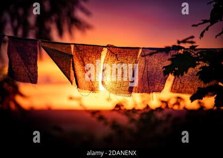 bandiere di preghiera nepalesi che sventolano durante il tramonto Foto Stock