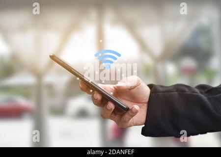 Tenere la mano utilizzando lo smartphone mobile con l'icona wifi. Idea per il social network di comunicazione aziendale. Foto Stock