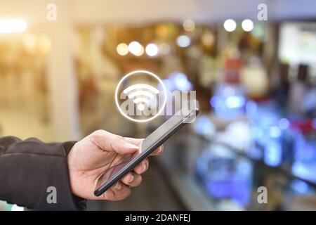 Tenere la mano utilizzando lo smartphone mobile con l'icona wifi. Idea per il social network di comunicazione aziendale. Foto Stock