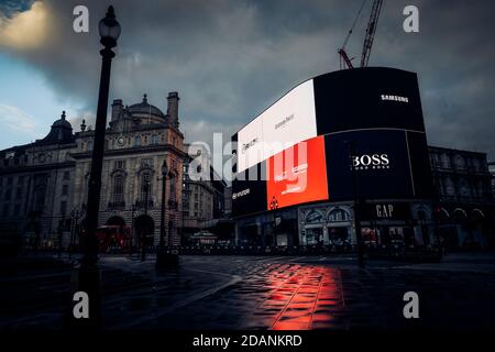 Al mattino presto in Lockdown Piccadilly Circus con nuvole scure nel cielo, Picadilly Circus segno neon illuminando con un riflesso rosso dal Coca- Foto Stock