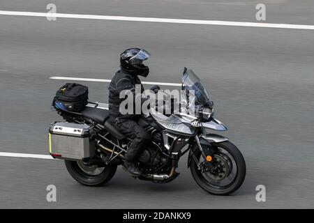 Triumph tiger moto e motociclista guida sulla M6 autostrada vicino Preston a Lancashire, Regno Unito. Foto Stock