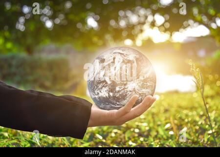 Concetto di ambiente: Mano di uomo d'affari che tiene la terra globale su sfondo bokeh verde. Elementi di questa immagine forniti dalla NASA Foto Stock