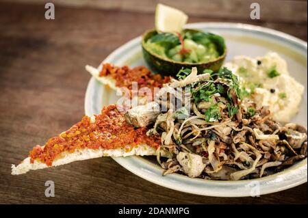 moderno brunch messicano di funghi fritti con guacamole e piccante pane tostato in pasta al peperoncino rosso e uova strapazzate Foto Stock