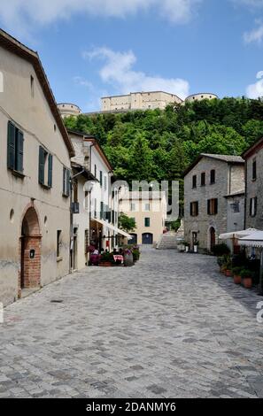 La strada principale di San Leo con il famoso castello sullo sfondo Foto Stock