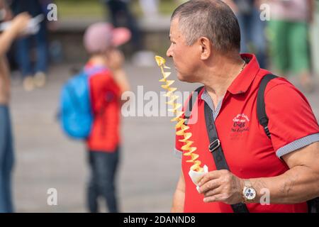 Uomo maturo con spuntino a piedi sulla strada Foto Stock