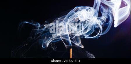 Fumo da una partita appena messo fuori, isolato su sfondo nero Foto Stock