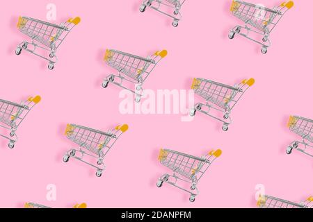 Concetto di amante dello shopping. Carrello con motivo senza cuciture su sfondo rosa. Composizione piatta, vista dall'alto Foto Stock