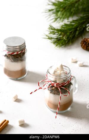 Gustoso regalo di Natale commestibile in vasetto di vetro per preparare una bevanda al cioccolato su sfondo chiaro. Delizie natalizie. Foto Stock