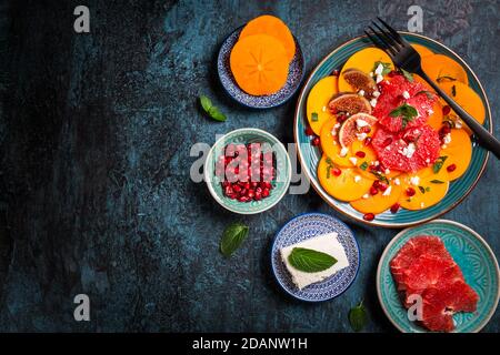 Insalata invernale sana - insalata di carpaccio di Persimmon con melograno, formaggio feta, pompelmo rosa e fichi Foto Stock