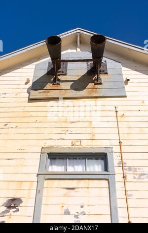 Foghorns al faro di Pigeon Point in California, che mostra le foghorns su un vecchio edificio giallo sbiadito. Giorno luminoso, soleggiato, cielo blu chiaro. Foto Stock