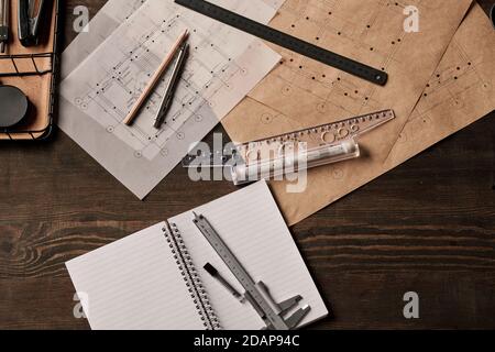 Vista dall'alto delle forniture per ufficio nel carrello, penna con matita e righelli su blueprint Foto Stock