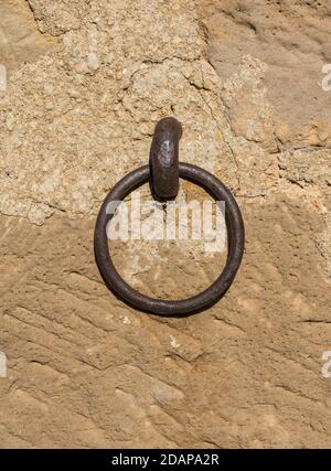 anello di ferro vecchio un po 'arrugginito incorporato in un muro di pietra, utilizzato per lasciare gli animali tethered come cavalli o muli Foto Stock