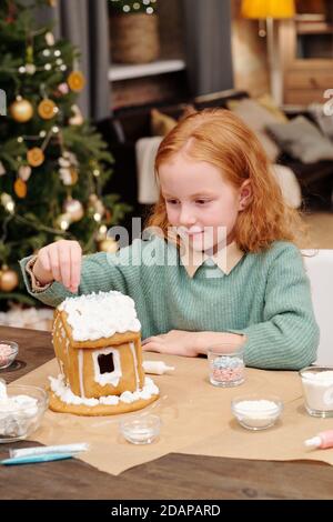 Cute girl sprinting tetto di casa pan di zenzero decorato con montato crema Foto Stock