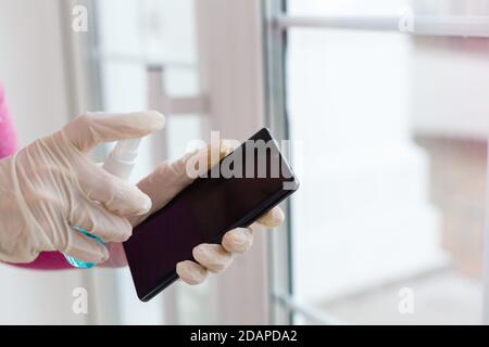 Mano di Donna pulizia dello schermo dello smartphone con alcol, prevenire l'infezione del virus Covid-19, la contaminazione di germi o batteri, pulire o pulire il telefono Foto Stock
