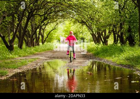 bambina in bicicletta in acqua puddle Foto Stock