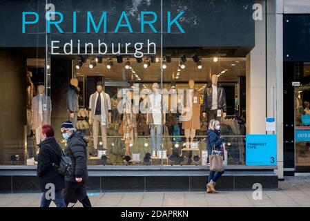 Donna che indossa una maschera facciale durante la pandemia del coronavirus in attesa al di fuori del negozio Primark su Prince Street, Edimburgo, Scozia, Regno Unito. Foto Stock