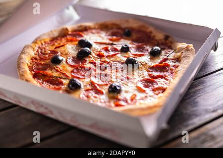 Pizza in una scatola di cartone sul tavolo pronta al cliente. Foto Stock