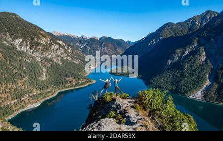 Due escursionisti si stendono le braccia in aria, vista di Plansee, Schojouechl sullo sfondo, escursione alla Schrofennas, Alpi Ammergau, Reutte distretto, Tirolo Foto Stock