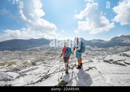 Due escursionisti guardano in lontananza, paesaggio di rocce carsiche, Funtenseetauern, Steinernes Meer, Berchtesgaden National Park Foto Stock