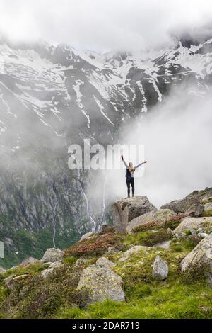 Paesaggio montano in nebbia, escursionista allunga le braccia in aria, vicino a Furtschaglhaus, Berliner Hoehenweg, Alpi Zillertal, Zillertal, Tirolo, Austria Foto Stock