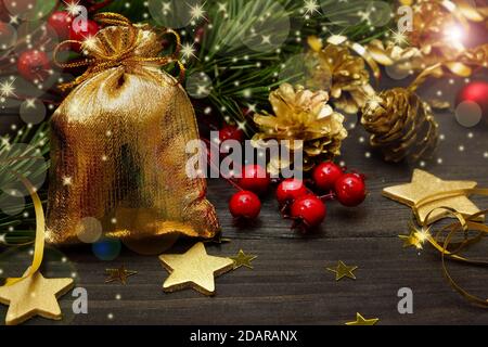 Carta anno nuovo. Borsa d'oro con regali e decorazioni dell'albero di Natale sul tavolo nero Foto Stock
