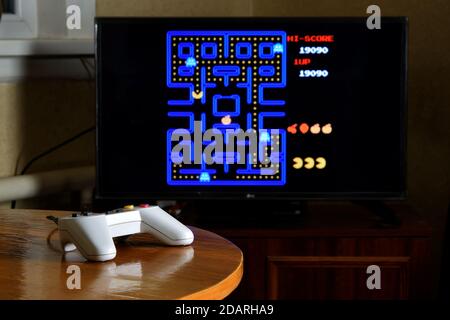 KHARKOV, UCRAINA - 12 NOVEMBRE 2020: Controller Dendy video game sul tavolo con il gioco PAC Man sul grande schermo Foto Stock