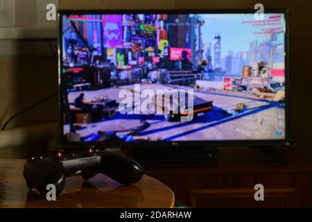 KHARKOV, UCRAINA - 12 NOVEMBRE 2020: Controller di videogiochi Gamesir g3s sul tavolo con Cyberpunk 2077 gioco su grande schermo Foto Stock