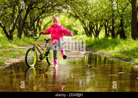 bambina in bicicletta in acqua puddle Foto Stock