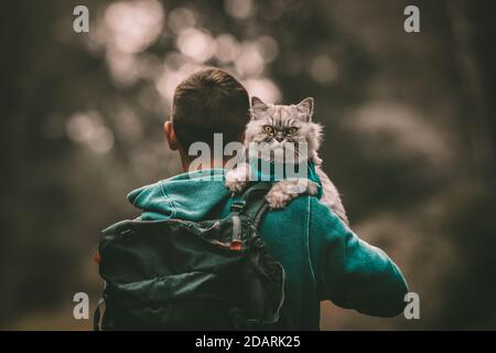 Persone e animali domestici. Escursioni con gatto. Gatto seduto sulle spalle. Uomo che passa il tempo con il suo amabile animale domestico. Camminare il gatto. Foto Stock