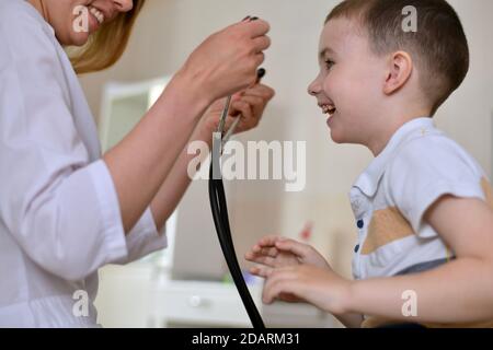 La donna dottore invita il ragazzo a provare il suo stetoscopio. Foto Stock