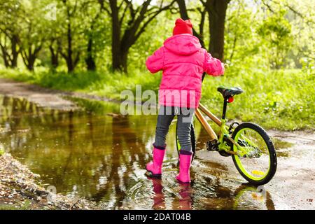 bambina in bicicletta in acqua puddle Foto Stock