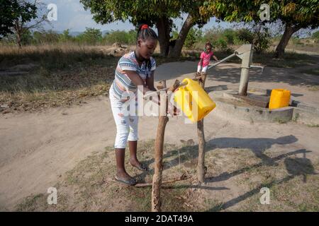 Ragazza giovane lavando le mani su gallone di acqua riciclata e adattato sui tronchi dell'albero come stazioni di lavaggio delle mani anche conosciute come rubinetti tippy, usando la saponetta locale Foto Stock