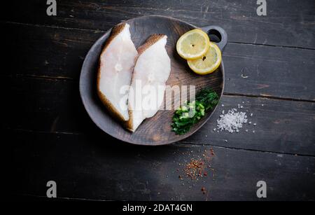 Bistecche di ippoglosso nero surgelate sul tagliere di legno. Cibo sfondo. Vista dall'alto Foto Stock
