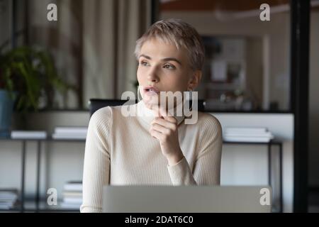 Primo piano su pensieroso giovane uomo d'affari che tocca il mento, meditando strategia Foto Stock