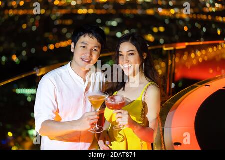 una coppia in un nightclub con cocktail su sfondo notturno della città Foto Stock