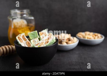 Torrone di organico a base di miele, pistacchi, nocciole, mandorle e i dadi su un rustico sfondo scuro. Foto Stock