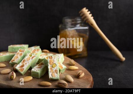 Torrone di organico a base di miele, pistacchi, nocciole, mandorle e i dadi su un rustico sfondo scuro. Foto Stock