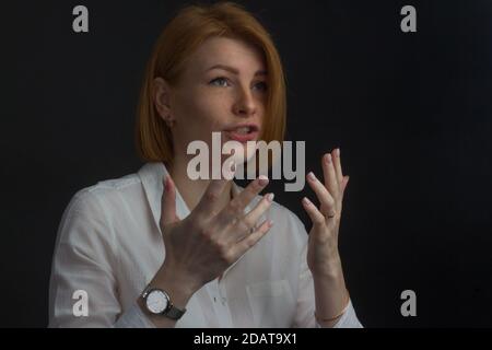 Giovane donna dai capelli rossi con frecche, emotivamente gesticulating usando il linguaggio dei segni Foto Stock