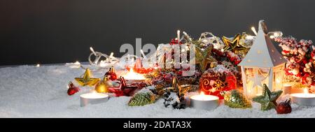 Composizione di Natale della lanterna ornamenti colorati sfere stelle candele e Abete rami sulla neve Foto Stock
