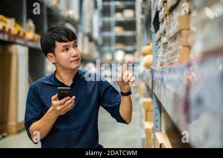 uomo di lavoro che utilizza lo smartphone per controllare l'inventario nel magazzino negozio Foto Stock