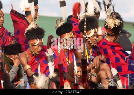 I tribisti di Naga indossano il loro abbigliamento tradizionale e si siedono insieme Kisama Village Arena a Nagaland India il 4 dicembre 2016 Foto Stock